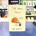 The Small Stuff book by Ian Bogost standing upright on a blue table in a store setting, with its cream-colored cover showing a pencil sharpener illustration and handwritten-style title text.