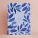 Notebook with blue leaf pattern and 'i'm so sorry' text on a beige background