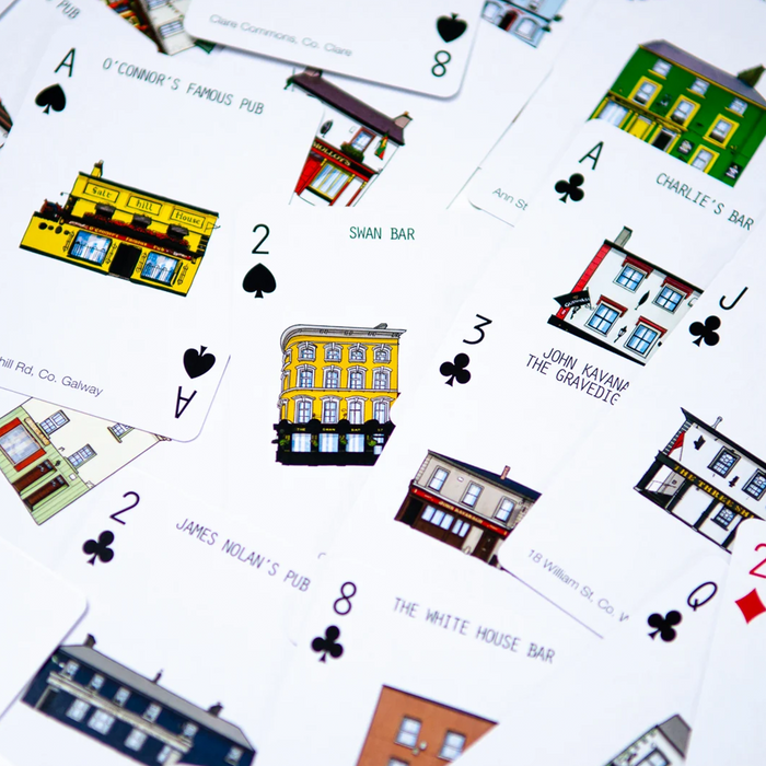 A close-up, angled view of playing cards featuring illustrated Irish pubs and street names on a white background.