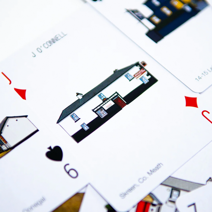A close-up, angled view of playing cards featuring illustrated Irish pubs and street names.