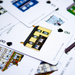 A close-up, angled view of a card game deck with illustrated playing cards fanned out on a white surface.