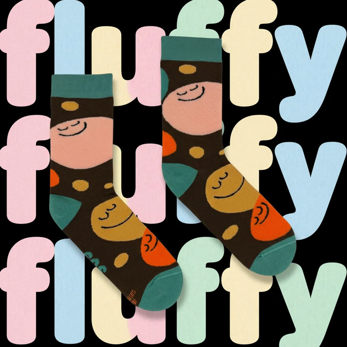 A pair of dark brown socks with a colorful cartoon pattern of smiling faces and dots, displayed against a black background with pastel-colored letters spelling 'fluffy'.