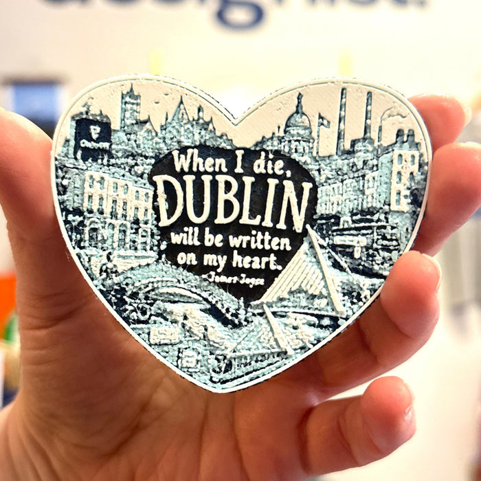 Heart-shaped magnet with Dublin quote held by a hand in front of a white background.