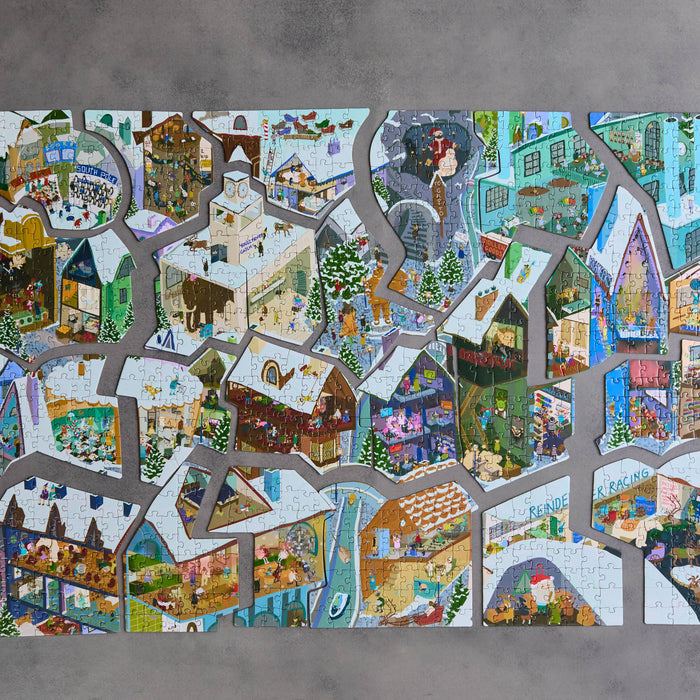 A completed jigsaw puzzle featuring a colorful, detailed winter village scene with houses, trees, roads, and small figures, displayed against a textured gray background.