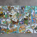 A completed jigsaw puzzle featuring a colorful, detailed winter village scene with houses, trees, roads, and small figures, displayed against a textured gray background.