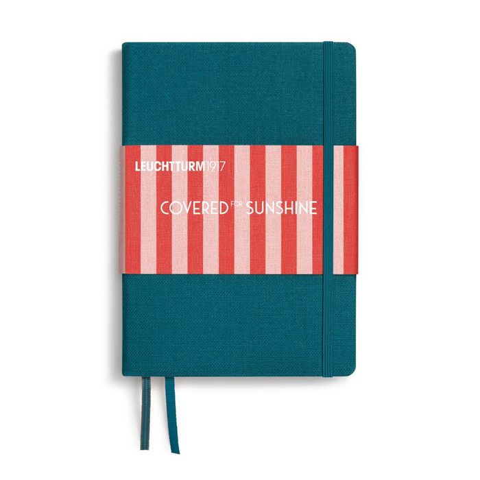A hardcover notebook with a teal blue cover, a red and white striped paper band across the middle, and white text reading 'LEUCHTTURM1917' and 'COVERED IN SUNSHINE'. A matching teal ribbon bookmark hangs from the bottom on a white background.