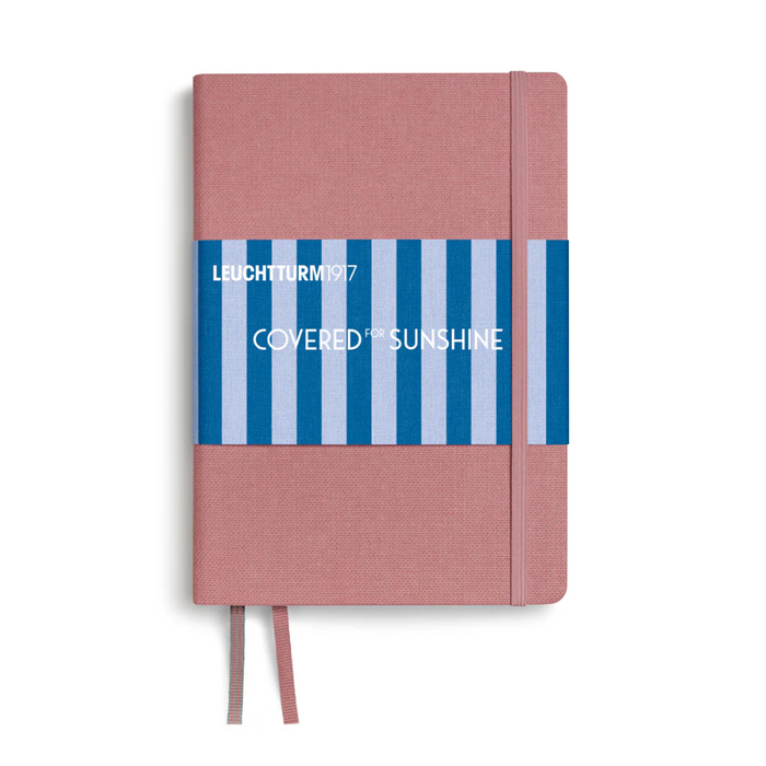 A Leuchtturm1917 hardcover notebook with a dusty pink textured cover, a blue and white striped paper band across the middle, and a matching pink ribbon bookmark, shown on a white background.