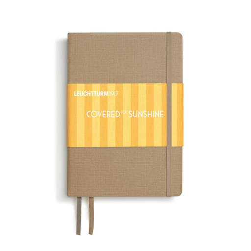 A Leuchtturm1917 notebook with a textured tan cover, a yellow and orange striped paper band wrapped around the middle, and a matching tan ribbon bookmark hanging from the bottom, shown on a white background.