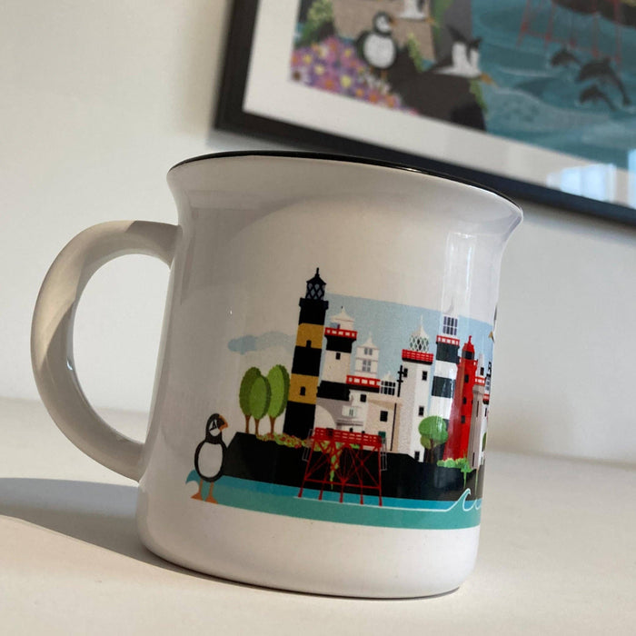 White mug with lighthouses and penguin design on a white surface.