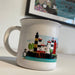 White mug with lighthouses and penguin design on a white surface.