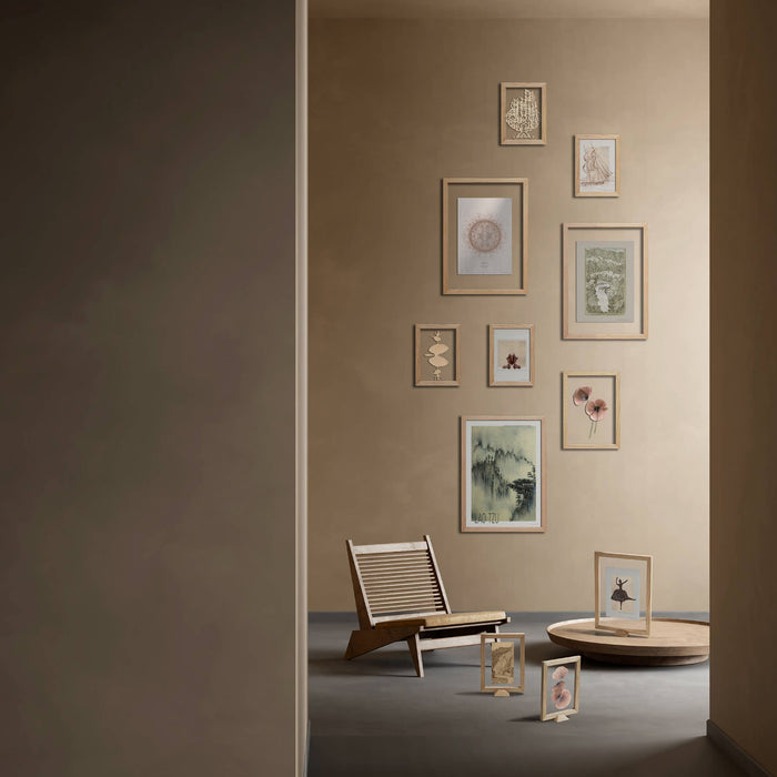 Wall with framed pictures and a chair in a room with a neutral color scheme