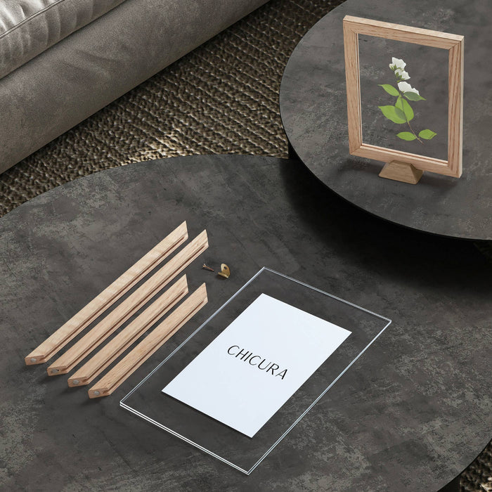 Round dark coffee table with deconstructed wooden frame with perspex sheet and paper featuring 'Chicura' logo on a textured floor.