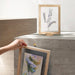 Framed artwork on a concrete surface with a neutral background