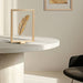 Framed artwork on a marble table beside a black chair against a white surface.