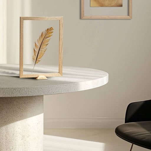 Framed artwork on a marble table beside a black chair against a white surface.