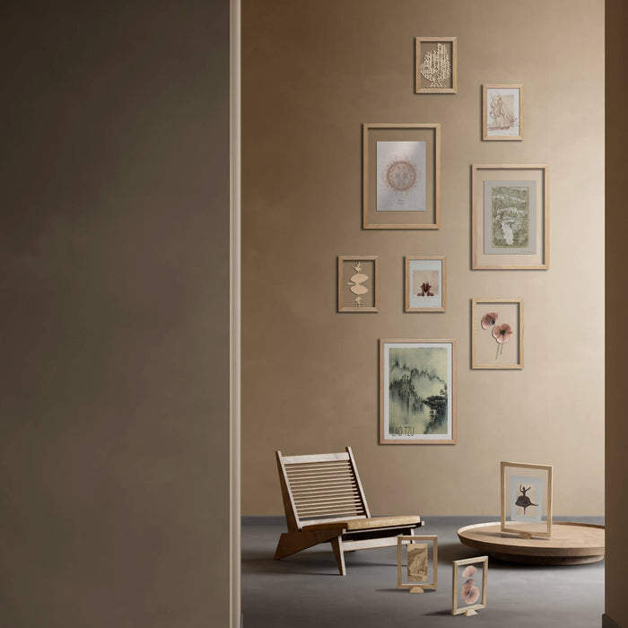 Wall with framed pictures and a chair in a room with a neutral color scheme