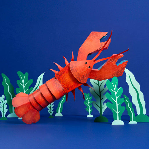 Red paper lobster with green plants on a blue background