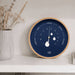 Wall clock with a blue face and wooden frame on a white shelf.
