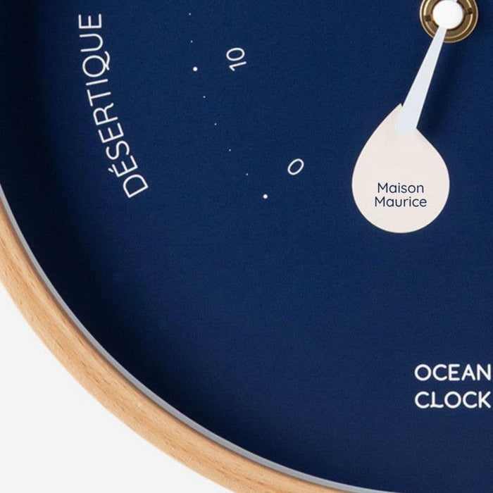 Close-up of a clock face with 'Desertique' branding and 'Maison Maurice' on a dark blue background.