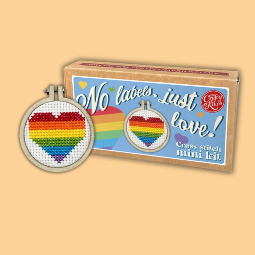 Cross-stitch mini kit with rainbow heart design and 'No labels, just love!' text on a beige background.