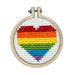 Cross-stitched rainbow heart in a wooden hoop on a white background