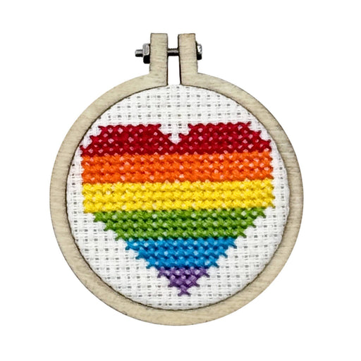 Cross-stitched rainbow heart in a wooden hoop on a white background