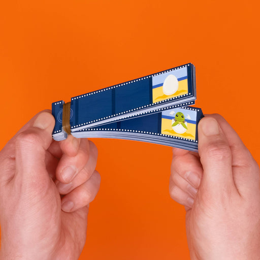 Two hands holding a stack of blue film strips with small printed illustrations, set against a solid orange background.