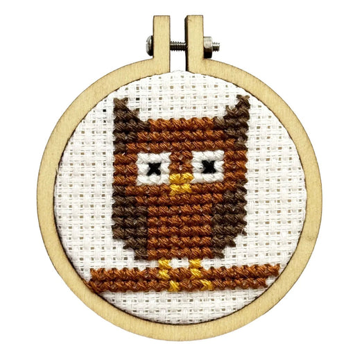 Cross-stitched owl design in a wooden hoop on a white background