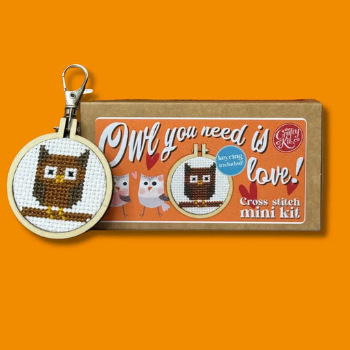 Cross stitch mini kit with owl design and packaging on an orange background