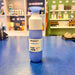 Blue Dopper water bottle with white cap on a blue surface, with shelves and products in the background.