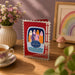 Birthday card with colorful fish design on a wooden table with a cup of tea and flowers.