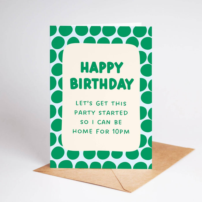 A green and white polka dot patterned birthday card with the text 'HAPPY BIRTHDAY LET'S GET THIS PARTY STARTED SO I CAN BE HOME FOR 10PM' in green lettering, displayed with a brown envelope on a light gray background.