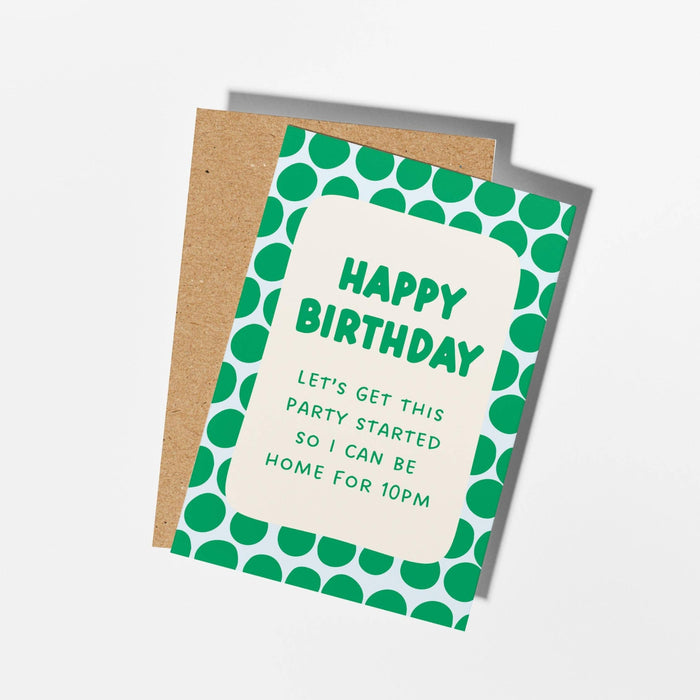A birthday card with a green and white polka dot border and a kraft paper envelope behind it, photographed on a clean white background.