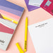 Yellow pen with 'Pawpear' branding on a pink surface with box and cards.