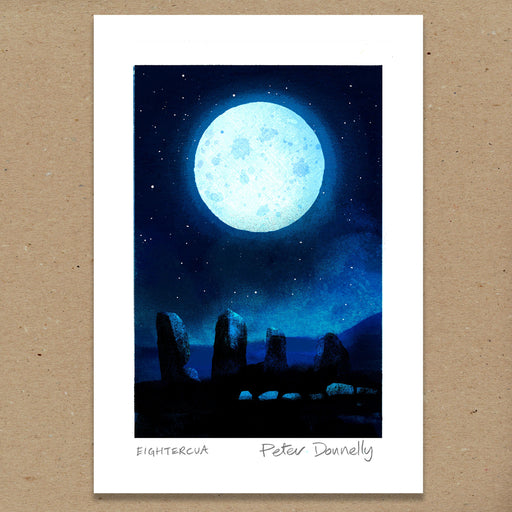 A square art print featuring a moonlit night scene with a large glowing full moon, stars, and dark stone monuments under a deep blue sky. The print has a wide white border and is photographed against a tan textured background.