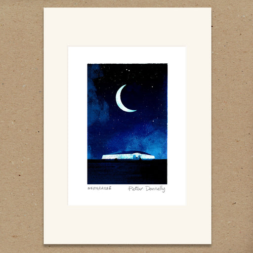 A matted art print featuring a watercolor illustration of a crescent moon in a starry night sky above a small house. The print has an off-white mat border and is displayed on a textured brown background.