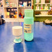 Light blue Dopper water bottle and white cup on a blue surface with a store interior in the background