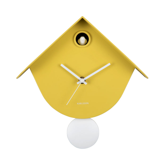 Yellow birdhouse-shaped clock with a white pendulum on a white background