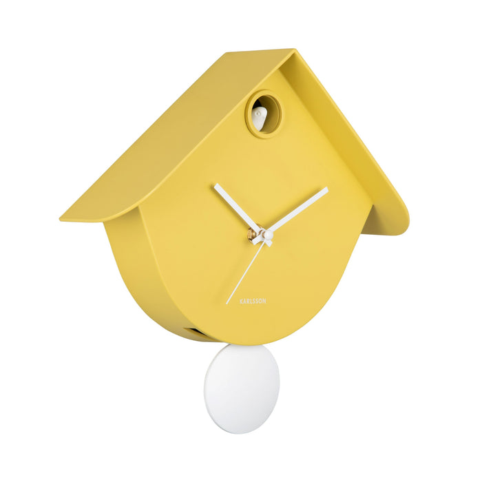 Yellow cuckoo clock with a white pendulum on a white background
