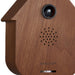 Wooden birdhouse-shaped device with a camera and speaker on a white background