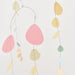 A minimalist mobile with thin metal wire arches and hanging organic-shaped paper pieces in pastel pink, yellow, peach, mint green, and light blue against a plain white background.