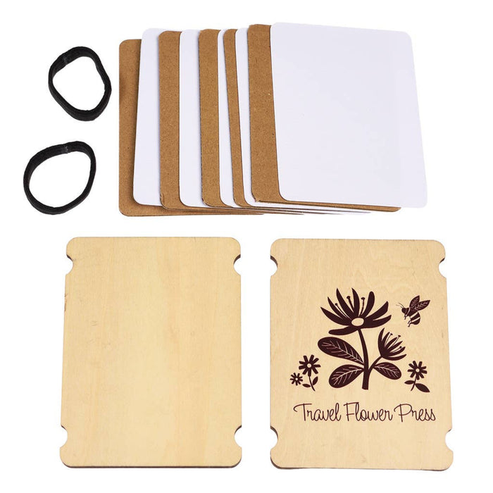 Travel flower press kit with wooden boards, white paper, rubber bands, and floral design on a white background.