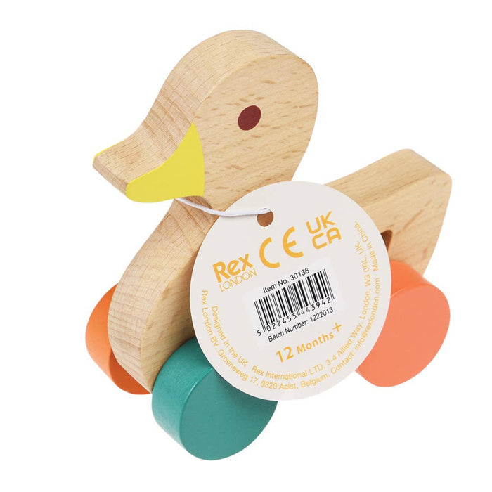 Wooden toy duck with colorful wheels and a label on a white background