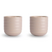 Two matching ribbed ceramic cups in a light warm beige color, shown side by side on a clean white background.