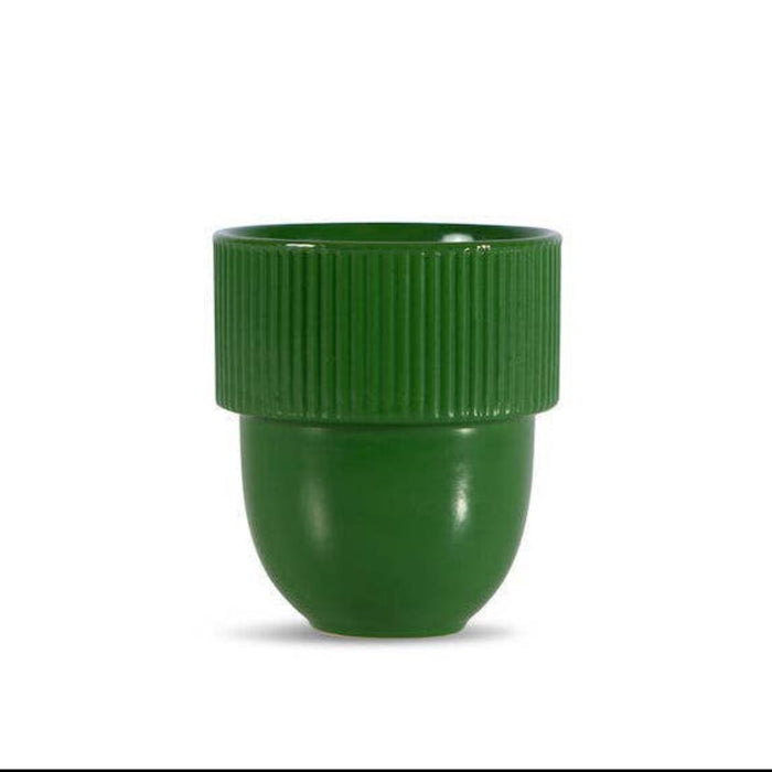 A small glossy green cup with a ribbed upper band, photographed on a plain white background.