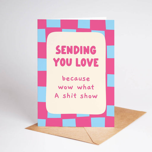 Greeting card with pink and blue checkered border and text 'Sending you love because wow what A shit show' on a white background.
