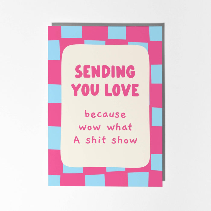 Card with pink and blue checkered border and text 'Sending you love because wow what a shit show' on a white background
