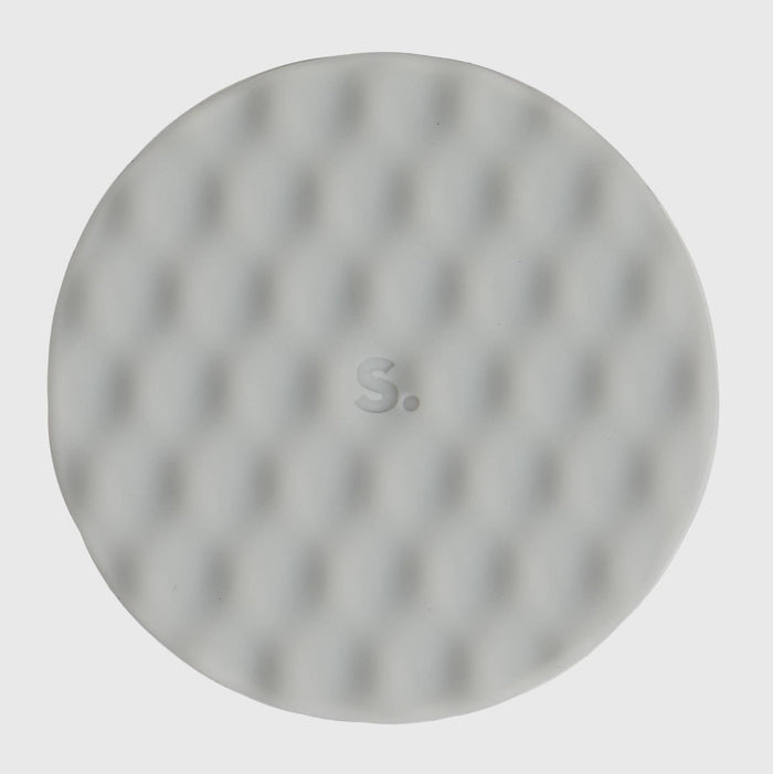 A round, light gray textured pad or disc with a subtle dimpled pattern and a small embossed 'S.' in the center, shown against a solid light gray background.