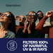 Several people outdoors wearing SolarOptics UV-blocking solar eclipse viewers, looking up at the sun. The image includes the SolarOptics brand name at the top and a dark blue banner at the bottom with the text 'FILTERS 100% OF HARMFUL UV & IR RAYS' and a 'Tested and Certified' badge.