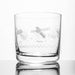A clear glass rocks tumbler with etched space-themed designs, including a satellite, stars, and the names 'COPU' and 'Chandra', shown on a reflective white surface against a white background.